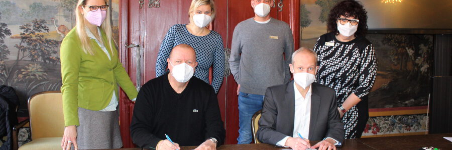 Gemeinsam für den Kindesschutz im Sport: Thorsten Schulte, Geschäftsführer des VfL Lüneburg (vorne links), und VfL-Präsident Uwe Walther unterzeichnen die Kooperationsvereinbarung gegen Kindeswohlgefährdung. Jutta Bauer, Leiterin des städtischen Fachbereichs Familie und Bildung (hinten von links), Sportreferentin Britta Herrschaft sowie Kreisjugendpfleger Christian Gebhardt und Ines Benne, Fachdienstleiterin Jugendhilfe und Sport beim Landkreis, schauen dabei über die Schultern. Foto: Hansestadt Lüneburg.