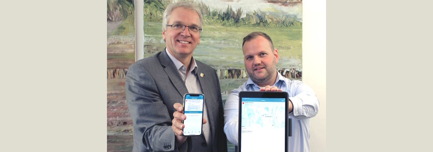 Landrat Jens Böther und Sascha Westermann, Fachgebietsleiter Brand- und Katastrophenschutz, zeigen die Warn-App BIWAPP. Foto: Landkreis Lüneburg (Archiv).