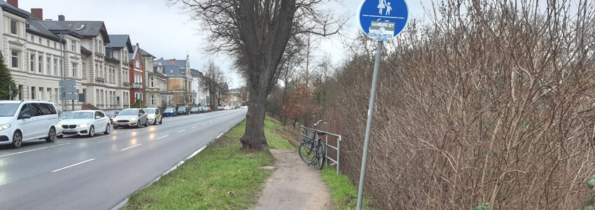 Foto: Lüne-Blog. Das ist der benutzungspflichtige(!) Radweg auf der Ostseite der Schießgrabenstraße zwischen Scharf- und Scholze-Kreuzung: Ein gemeinsamer Pfad - die Bezeichnung Weg wäre hier übertrieben - für zu Fuß Gehende und Radfahrende. Der stark abschüssige Weg führt hier hinunter zum Ilmenaufer und bei der Scholzekreuzung wieder nach hinauf auf Straßenhöhe. Bei Bei diesem Verkehrszeichen 240 müssen Radfahrende besondere Rücksicht auf Personen zu Fuß nehmen und ihre Geschwindigkeit entsprechend anpassen. 