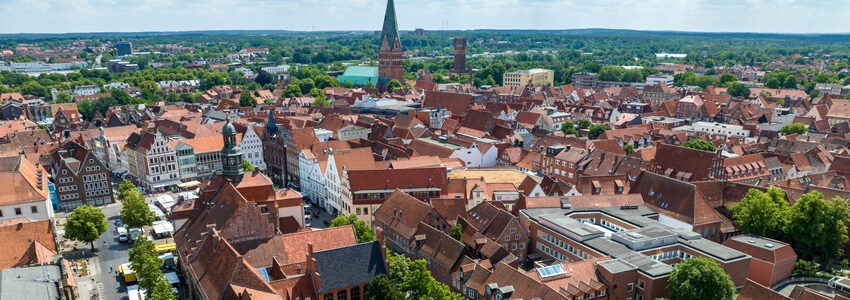 Foto: Hansestadt Lüneburg. Blick über das Rathaus mit Marktplatz, Johanniskirche und Wasserturm. Luftbild.
