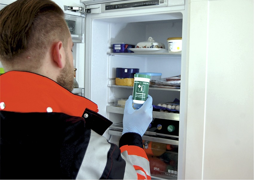 Foto: acavi GmbH, Bremen. Notfallsanitäter vor dem geöffneten Kühlschrank: Hier ist die Notfalldose schnell zu finden. 
