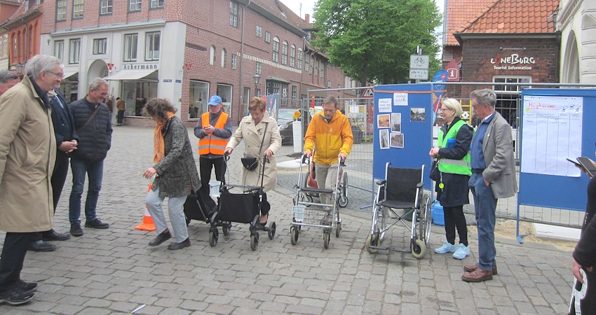 Foto: J. Korn. "Drei, zwo, eins ..." - gleich geht es los! Von links: Gerd Borchers (FUSS e.V.), Wolfgang Goralczyk (verdeckt), Reiner Netwall (ALA e.V.) Am Start machen sich schon mal bereit  Karin Fischer, Christel John und Markus Moßmann. Daneben Julia Born und Dr. Michael Perschmann , Ratsmitglied für Bündnis 90/Die Grünen. Manbeachte die Gefäße mit Wasser, die jeweils an der Gehhilfe angebracht sind. Es gilt, schnell zu sein, aber möglichst wenig zu verschütten!