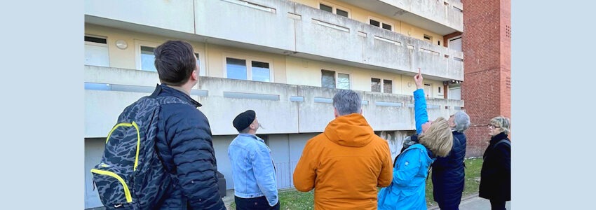 Ortstermin in Kaltenmoor, 19. März 2025. OB Claudia Kalisch zeigt im Kreis von Begleitpersonen auf Schäden am Gebäude. Foto: Hansestadt Lüneburg.