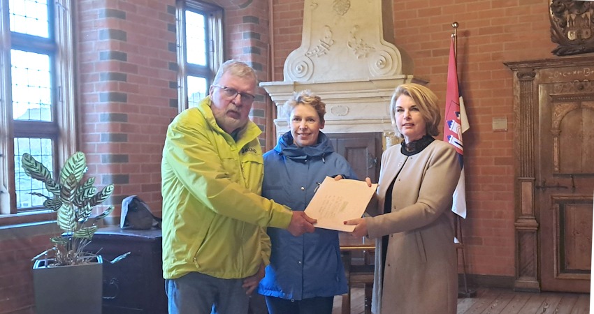 Foto: BUND, NABU Lüneburg. Lüneburg. 16. März 2026: Bernhardt Stilke (BUND) und Anette Reinhardt (NABU) übergeben die Petition zum Stopp des Feuerwerks an den Sülzwiesen an OB Claudia Kalisch.