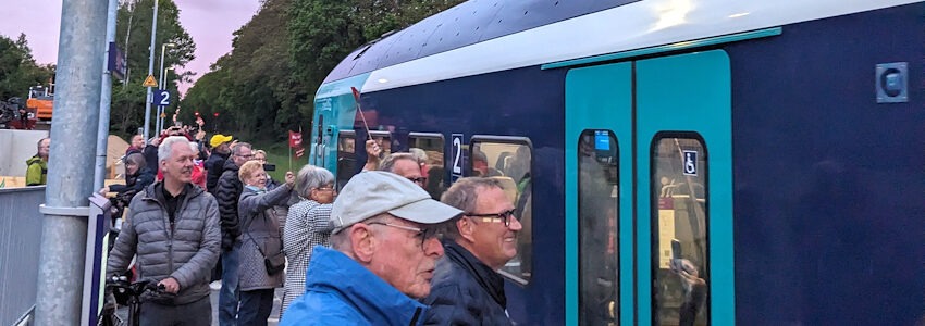 Foto: VCD Elbe-Heide. Frühmorgens kurz nach 5 Uhr am Montag, 18. Mai 2026: Adendorf heißt den ersten Zug aus Lübeck im Bahnhof willkommen. Ganz rechts im Bild: Thomas Maack, Bürgermeister der Gemeinde Adendorf.