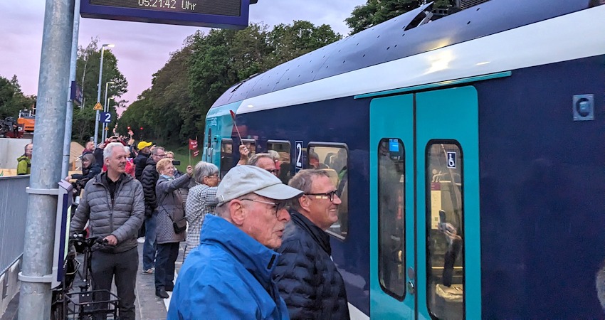 Foto: VCD Elbe-Heide. Frühmorgens kurz nach 5 Uhr am Montag, 18. Mai 2026: Adendorf heißt den ersten Zug aus Lübeck im Bahnhof willkommen. Ganz rechts im Bild: Thomas Maack, Bürgermeister der Gemeinde Adendorf.