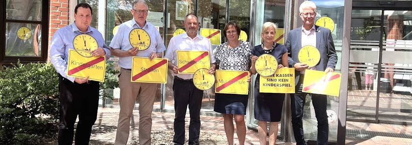 Foto: Landkreis Lüchow-Dannenberg. Von rechts: Holger Mertins, Bürgermeister der Stadt Hitzacker, Landrätin Dagmar Schulz und weitere Verantwortliche aus Landkreis und den drei Samtgemeinden. Sie zeigen bei der Aktion "Kommunen am Limit", wo es fehlt, wenn sie  finanziell nicht bedarfsgerecht ausgestattet werden: Kindergärten, Straßen, Musikschule, Schwimmbad.