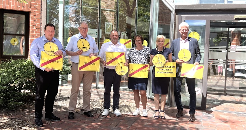 Foto: Landkreis Lüchow-Dannenberg. Von rechts: Holger Mertins, Bürgermeister der Stadt Hitzacker, Landrätin Dagmar Schulz und weitere Verantwortliche aus Landkreis und den drei Samtgemeinden. Sie zeigen bei der Aktion "Kommunen am Limit", wo es fehlt, wenn sie finanziell nicht bedarfsgerecht ausgestattet werden: Kindergärten, Straßen, Musikschule, Schwimmbad.