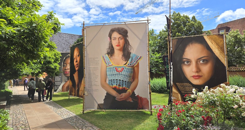 Foto: Lüne-Blog. Die Ausstellung „WÜRDE!“ ist vom 9. bis 18. Juni 2026 im Rathausgarten Lüneburg zu sehen: Großformatige Porträts von Frauen mit Zuwanderungsgeschichte und persönliche Statements setzen ein Zeichen für Würde und gesellschaftliche Teilhabe.