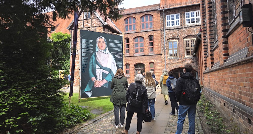 Foto: Lüne-Blog. Die Ausstellung „WÜRDE!“ ist vom 9. bis 18. Juni 2026 im Rathausgarten Lüneburg zu sehen: Großformatige Porträts von Frauen mit Zuwanderungsgeschichte und persönliche Statements setzen ein Zeichen für Würde und gesellschaftliche Teilhabe.