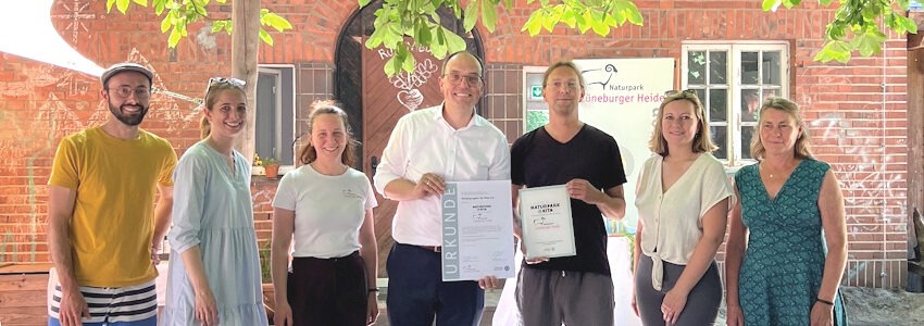 Foto: Naturpark Lüneburger Heide. Freuen sich gemeinsam über die Auszeichnung - von links: Malte Groß, Vorstandsmitglied der Rübe e.V.; Anna Bauseneick MdL; Annika Drews-Shambroom, Bildungsverantwortliche beim Naturpark Lüneburger Heide; Steffen Gärtner, Vorstandsvorsitzender Naturpark Lüneburger Heide; Matthias Wöhlk, Leiter der Rübe Oedeme; Jule Grunau, ehrenamtliche Bürgermeisterin der Stadt Lüneburg und Birte Hansen, Geschäftsführerin der Rübe e.V.