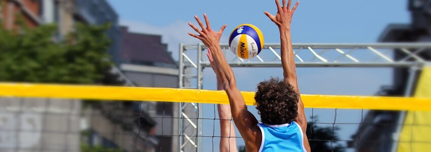 Foto: Tania Van den Berghen, Pixabay. Beach Volleyball-Spiel zwischen zwei Häusern.