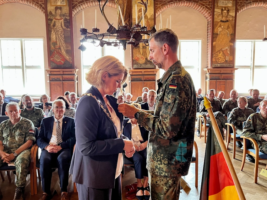 Foto: Hansestadt Lüneburg. Als Zeichen der Verbundenheit und besonderen Anerkennung verlieh Oberstleutnant Moos die Ehrennadel des Aufklärungslehrbataillons 3 „Lüneburg“ an Claudia Kalisch – stellvertretend für die Hansestadt Lüneburg.